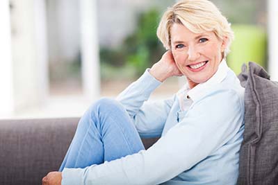 woman with dental veneers smiling on her couch